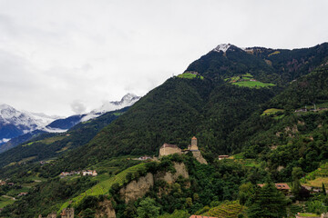 Panorama with Tyrol Castle (Schloss Tirol) and snowcapped mountain summit Mutspitze on a cloudy day in autumn in Tirol (Dorf Tirol) in South Tyrol, Italy