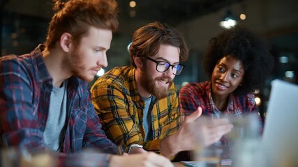 Young Diverse Team Collaborating on Laptop in Modern Office or Cafe Setting - Powered by Adobe