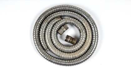 Coiled Metal Shower Hose on White Background, Close-Up View.