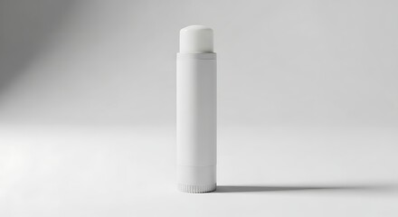 White lip balm tube standing upright on a clean white surface casting a soft shadow, showcasing minimalist beauty and skincare simplicity.