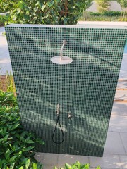 Outdoor Swimming pool shower with a mosaic tile wall with overhead shower head and a handheld shower wand.
Public Facility, Resort Or Hotel Amenity
Body Hygiene before Swimming in Pool Water