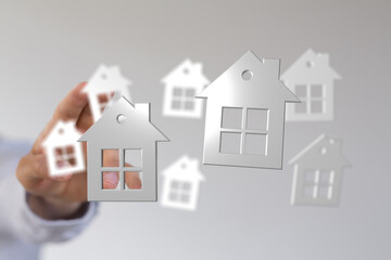 Hand holding house cutouts, representing homeownership and the real estate market. Perfect for illustrating concepts of buying, selling, and inv