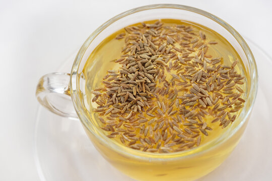 Black cumin seeds,shah jerra,Nigella sativa and its extracted water in a transparent glass on brown wooden surface. Close up and Selective focus.
