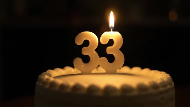 A video capturing a 33rd birthday celebration, highlighting a cake with glowing number "33" candles against a dark background, emphasizing a moment of wishing or celebration.
