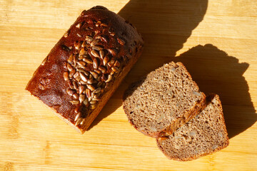 sliced rye bread with bran and seeds next to 2 slices of bread on a wooden surface, top view