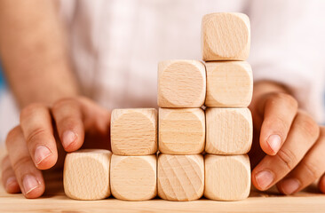 A close-up shot of hands arranging wooden cubes into a staircase, representing progress, goals, and achievement. Perfect for concepts like busin