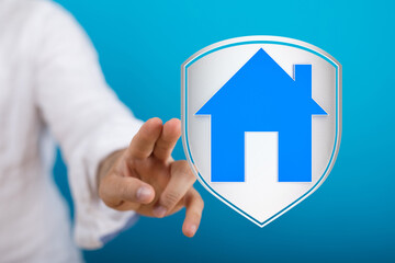 Obraz premium A hand reaching towards a shield with a house icon representing home protection, insurance, and safety. This stock photo conveys concepts of sec
