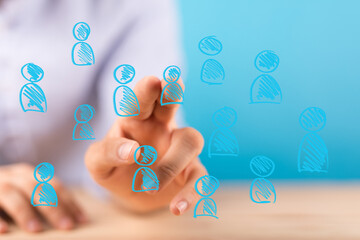 Hand selecting a person icon from a group, representing team selection, networking, human resources.
