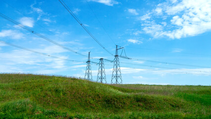 Power lines in a green field in the sunny summer day. Electrical substation.
