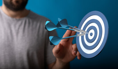 Close-up shot of a man's hand throwing darts and hitting the bullseye on a target. Concept of...