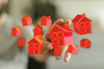 A hand reaching out with red 3D houses floating, symbolizing real estate, investment, property, and home ownership, suitable for marketing and b
