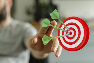 Close-up of a person's hand reaching for a dartboard, representing strategic goals, success, and...