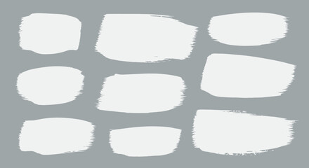 Collection of nine artistic white brush stroke shapes presented on a smooth gray background