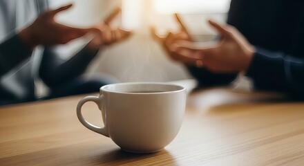 Close up of a coffee mug on a wooden table with blurred people talking in the background