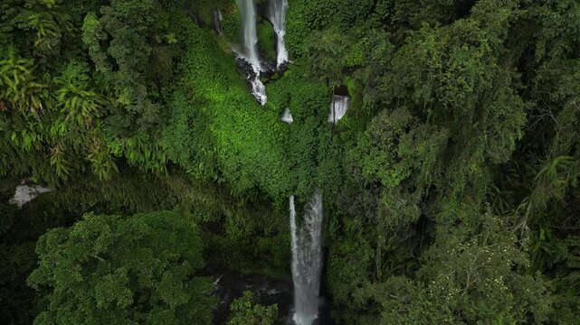 Drone aerial view of Sendang Gile Waterfall in Senaru, Lombok, Indonesia, with cascading water, tropical rainforest and lush green surroundings.
