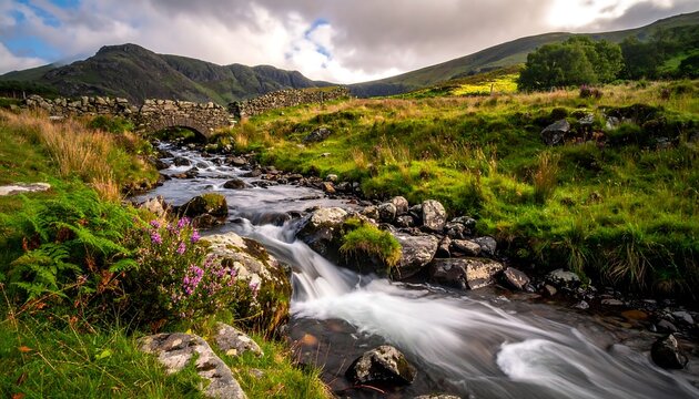 A flowing stream beneath a stone bridge against rolling hills and a cloudy sky