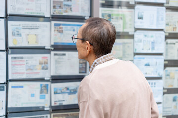 不動産広告を見るシニア男性