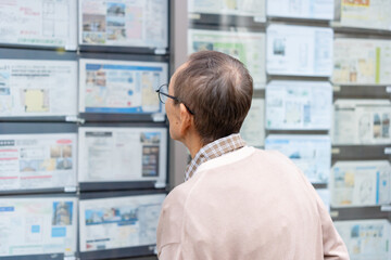 不動産広告を見るシニア男性