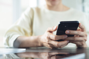 Closeup, woman using smartphone for online shopping, digital banking, social network via mobile app. Business woman using mobile phone searching the information, working on laptop at office