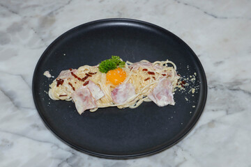 A delicious plate of spaghetti carbonara with an egg yolk and fresh parsley garnish