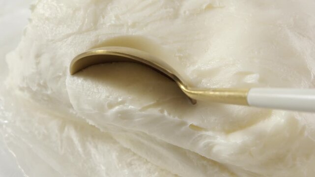 Macro video of spoon scooping creamy shea butter, styled to show skincare product texture for cosmetic ingredient visuals.