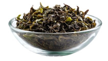 A transparent bowl overflowing with vibrant green tea leaves against a crisp white background