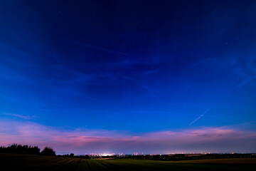 A stunning sunset over the Czech countryside, with colorful fields and a vibrant night sky emerging. Perfect for landscape photography, rural scenery, and dramatic sky compositions.