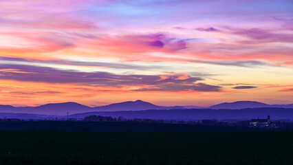 A stunning sunset over the Czech countryside, with colorful fields and a vibrant night sky emerging. Perfect for landscape photography, rural scenery, and dramatic sky compositions.