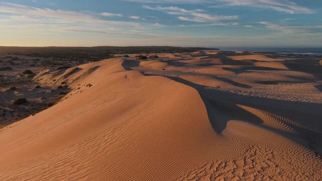 Aerial drone footage of Eyre Peninsula&rsquo;s desert sand dunes at sunset in South Australia, showcasing golden light, sweeping textures, and the stunning contrast of rugged outback beauty and coast 4K