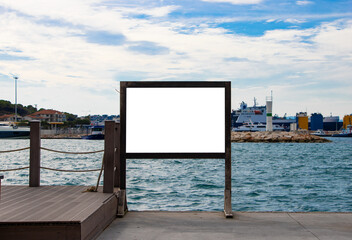 Blank white information board mock-up mounted on wooden frame by coastal dock, captured in seaside...