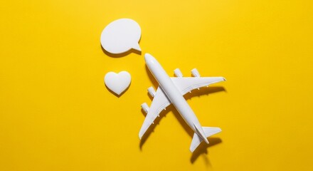 Overhead shot features a white toy airplane, heart, and speech bubble on a vibrant yellow backdrop.