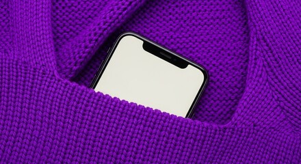 A modern mobile phone is snuggly nestled within the folds of a soft, purple knitted fabric material.