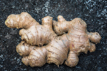 Single ginger root rests on a dark, textured background