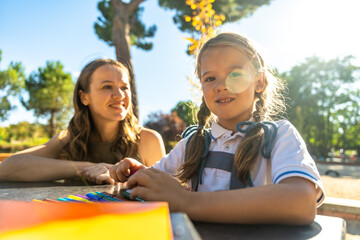 Mother and daughter drawing outdoors at school