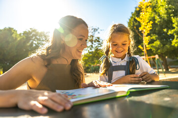 Mother and daughter reading book together outdoors