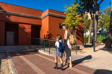 Mother walking daughter to school with backpack