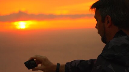 Sunset photographer action camera recording vibrant golden sunrise over foggy mountain view - Powered by Adobe