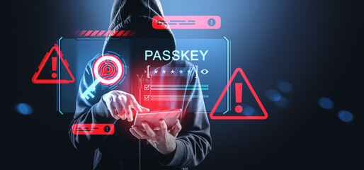 Hacker in hoodie using tablet with digital passkey interface and red warning signs on futuristic cybersecurity background in blue tones..