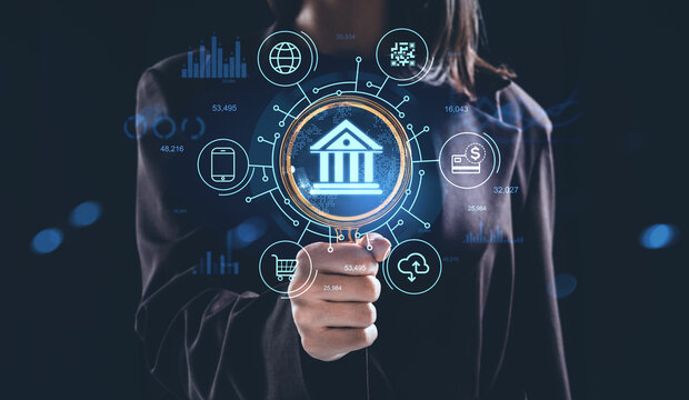 Futuristic banking concept with hologram interface icons and financial technology graphics on dark background held by businesswoman.