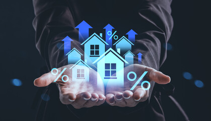 Holographic real estate growth concept with floating house icons and percentage signs in businessman hands on dark background.