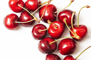 Fresh red cherries with stalks on white background. Natural fruit composition symbolizing summer harvest, healthy eating, freshness, vitamins, sweetness and organic seasonal food concept.