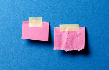 Pieces of pink paper memo reminder notes with adhesive tape and copy space for text on blue background