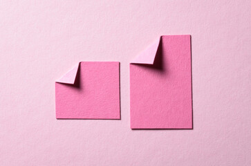 Pieces of paper notes or sheets with folded edge dog-ear earmark and copy space for text on light pink background, top view flat lay