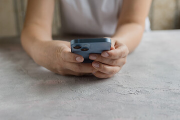 Close-up of a woman's hand holding a smartphone at a cafe table. Working or studying using a phone or gadget