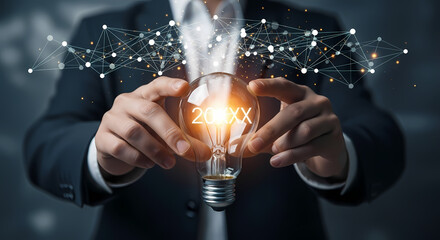 A businessman holds a glowing lightbulb with the year 20XX, symbolizing innovation, ideas, and the future of technology.