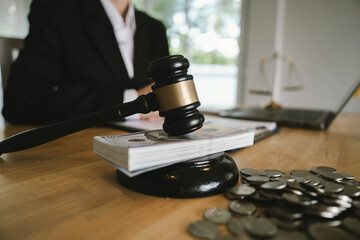 Judge’s gavel placed on dollar bills and coins with a businessperson signing legal documents, symbolizing law, money, and justice.