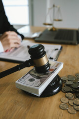 Judge’s gavel placed on dollar bills and coins with a businessperson signing legal documents, symbolizing law, money, and justice.