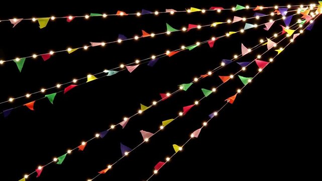 Festive string lights and colorful triangular flags hanging against a dark night sky.Bright illumination creates a joyful celebration atmosphere. Concept of holiday and outdoor event decoration.