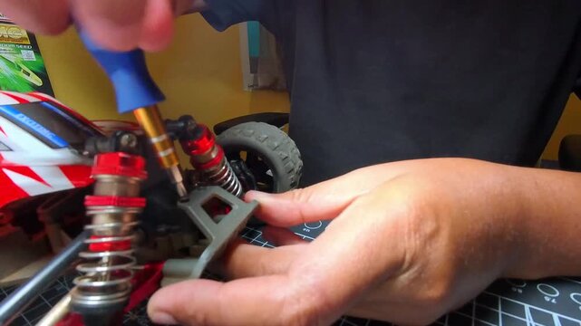 Footage of Hand motion unscrew a bolt on a remote control car body. Videography of repair and maintenance of hobby toys by a mechanic. High-Quality 4K Resolution Footage