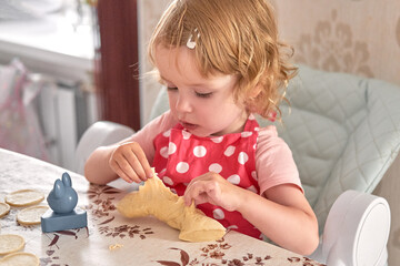 Little girl in a red polka dot apron plays with dough at the kitchen table.
Toddler learns baking through sensory play and fine motor skills.
Homemade cooking moment captures childhood curiosity